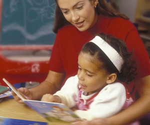 Teacher Reading With Child In Classroom